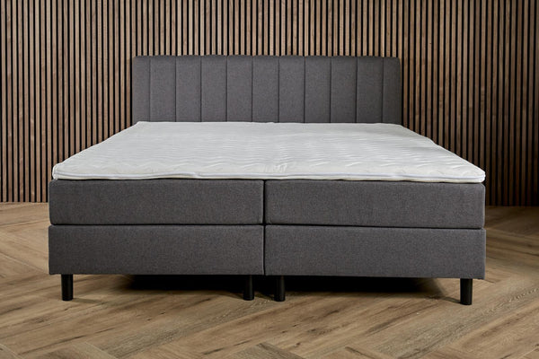 Antraciet Boxspring Comfort with built-in storage from Bedden.nl, showing the plush fabric and storage compartments underneath.