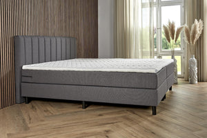 Dark gray Boxspring Comfort bed with built-in storage drawers, featuring a plush headboard and modern design from Bedden.nl.